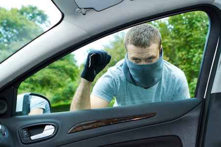 Thief wearing black clothes and leather coat stealing a car