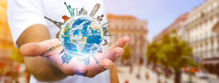 Young man holding the planet earth in his hands surrounded by famous monuments of the worldの写真素材