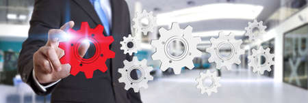 Businessman moving digital gears with his hand in his officeの写真素材