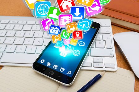 Modern mobile phone in office with icons flying overの写真素材