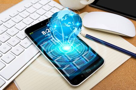 Modern mobile phone in office with cyber world flying overの写真素材