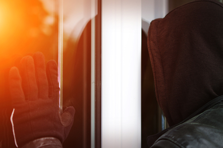 Burglar wearing black clothes and leather coat breaking in a houseの写真素材