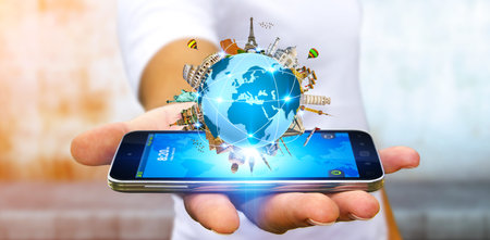 Young man holding the planet earth surrounded by famous monuments of the world over his mobile phone