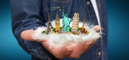 Young man holding a cloud full of famous monuments of the world in his handsの写真素材