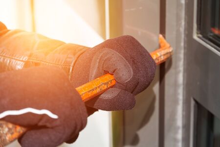 Burglar trying to break into a house with a crowbarの写真素材