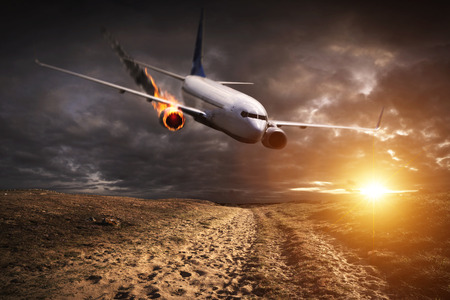 White plane with engine on fire about to crash in the landscapeの写真素材