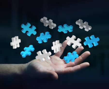 Businessman holding flying puzzle pieces in his hand 3D renderingの写真素材