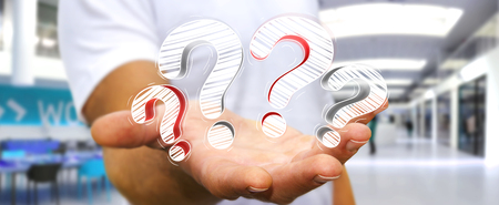 Businessman on blurred background holding hand drawn question marks in his handの写真素材