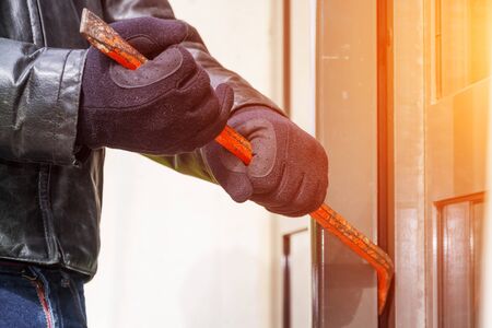 Burglar trying to break into a house with a crowbarの写真素材