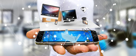 Businessman on blurred background holding flying desk laptop phone and tablet in his hand 3D...