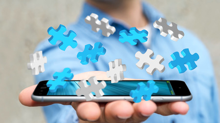 Businessman holding flying puzzle pieces on his mobile phone 3D renderingの写真素材