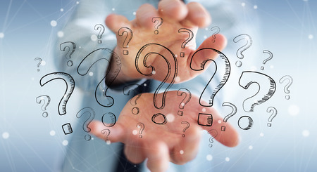 Businessman on blurred background holding hand drawn question marks in his handの写真素材