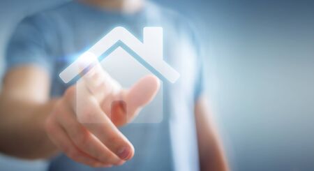 Businessman on blurred background touching 3D rendering icon house with his fingerの写真素材