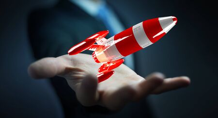 Businessman on blurred background holding red rocket in his hand 3D renderingの写真素材