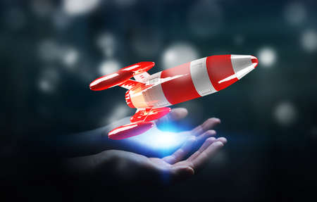 Businessman on blurred background holding red rocket in his hand 3D renderingの写真素材