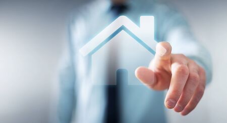 Businessman on blurred background touching 3D rendering icon house with his fingerの写真素材