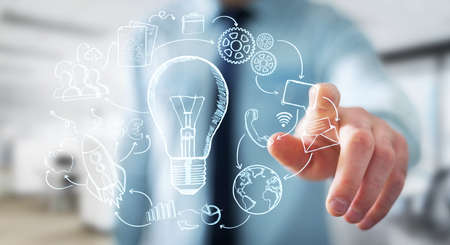 Businessman touching hand drawn lightbulb with his fingers with multimedia icons flying aroundの写真素材