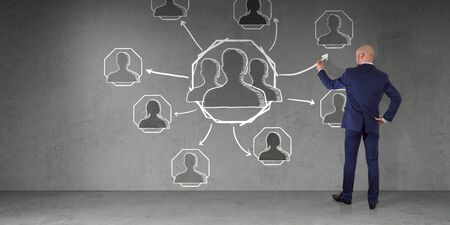 Businessman in modern interior drawing social network sketch on a wall 3D renderingの写真素材