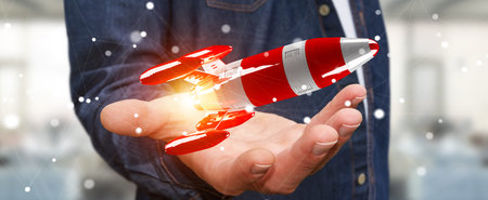 Businessman on blurred background holding red rocket in his hand 3D rendering