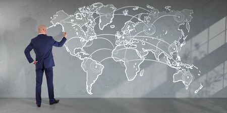Businessman in modern interior drawing manuscript world map connection on a wall 3D renderingの写真素材