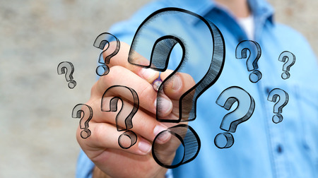 Businessman on blurred background drawing hand drawn question marksの写真素材