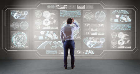 Businessman in modern interior using graph screens interface on a wall 3D renderingの写真素材