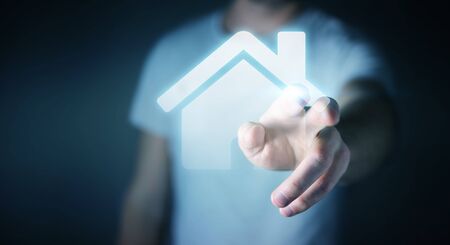 Businessman on blurred background touching 3D rendering icon house with his fingerの写真素材