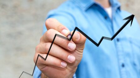 Businessman on blurred background drawing hand-drawn arrow going upの写真素材