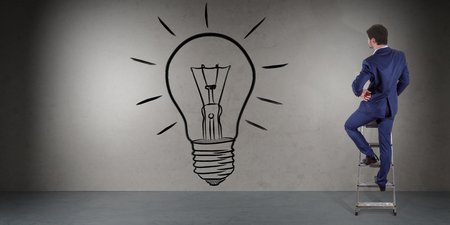 Businessman in modern interior watching a lightbulb on a wall 3D renderingの写真素材