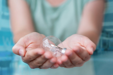 Businesswoman on blurred background holding a lighbulb in her handの写真素材