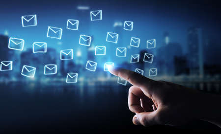 Businessman on blurred background holding and touching floating emails sketchの写真素材