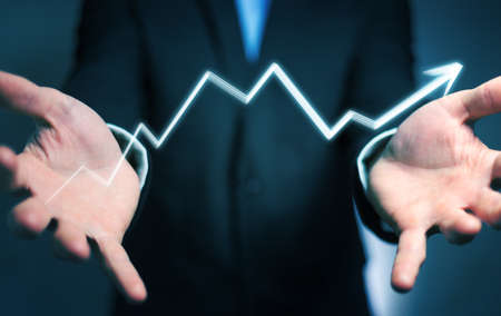 Businessman on blurred background holding hand-drawn arrow going upの写真素材