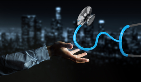 Businessman on blurred background holding and touching floating stethoscope 3D renderingの写真素材