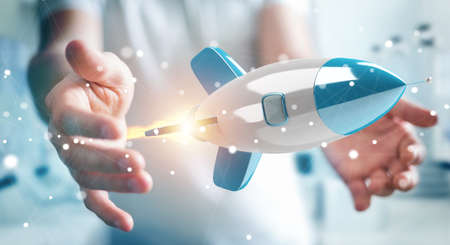 Businessman on blurred background holding and touching a rocket 3D renderingの写真素材