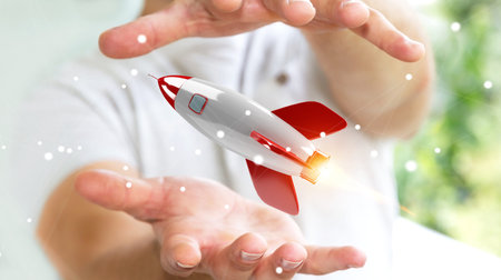 Businessman on blurred background holding and touching a rocket 3D rendering