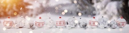 White and red christmas baubles lined up on snow background 3D renderingの写真素材