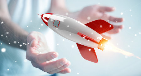 Businessman on blurred background holding and touching a rocket 3D rendering