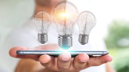 Businessman on blurred background connecting modern lightbulbs with connections 3D renderingの写真素材