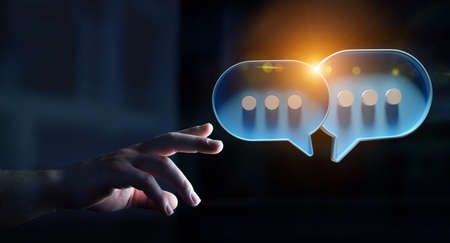Man in dark touching with his fingers digital colorful speech bubbles talk icons. Minimal conversation or social media messages floating in front of businessman hand. 3D renderingの写真素材