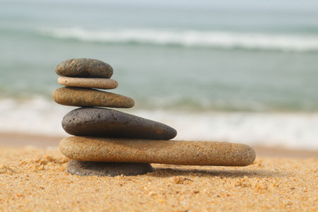 Pile of smooth stones on sand with waves