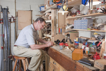 Man working at home workbench surrounded by equipment