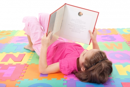 Girl reading book on alphabet letters floor mat  Isolated on white の写真素材