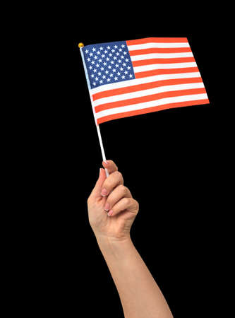 Female hand holding American flag, isolated on black backgroundの写真素材