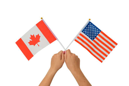 Female hand holding Canadian and American flags, isolated on white backgroundの写真素材