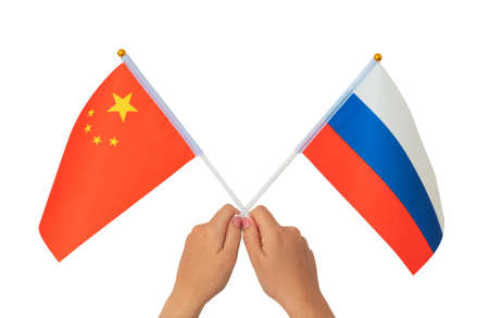 Female hand holding Russian and Chinese flag, isolated on white backgroundの写真素材