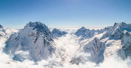 Mountain peaks shine under the sun above the cloudsの写真素材