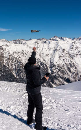 Drone taking off from male hand on the top of snowy mountain in winterの写真素材