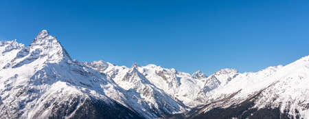 Panoramic view of winter snowy mountains in Caucasus region in Russia with blue skyの写真素材