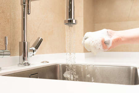 the sink in the kitchen is washed with a sponge in the foam of detergentの写真素材