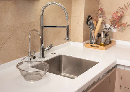 Modern kitchen with steel sink faucet and white worktopの写真素材